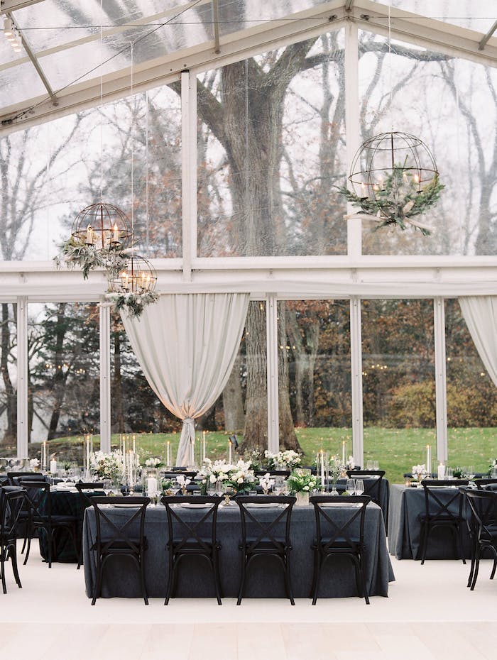 Stilvolle Tischdekoration für Hochzeit, graue Tischdecken, weiße Blumen und Kerzen, große runde Kronleuchter