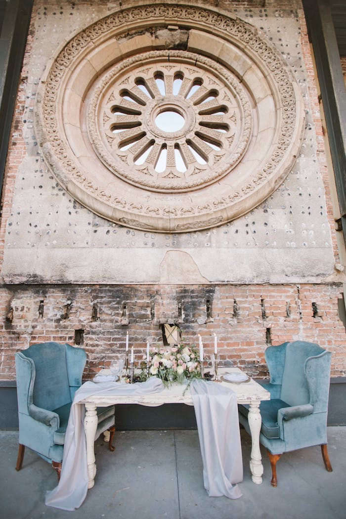 Hochzeit Tischdeko in Landhaus, weißer Holztisch mit Altersspuren, weiße Rosen und Kerzen, blaue Sessel