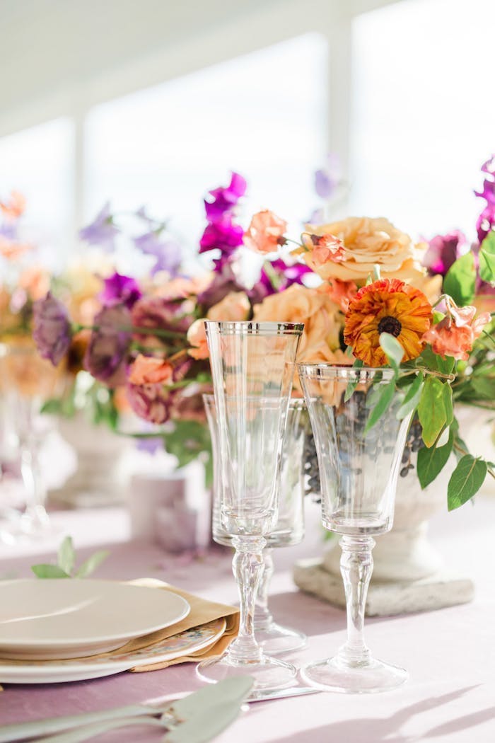 Tischdeko in warmen Pastellfarben, Weingläser mit silbernem Rand, viele Blumen