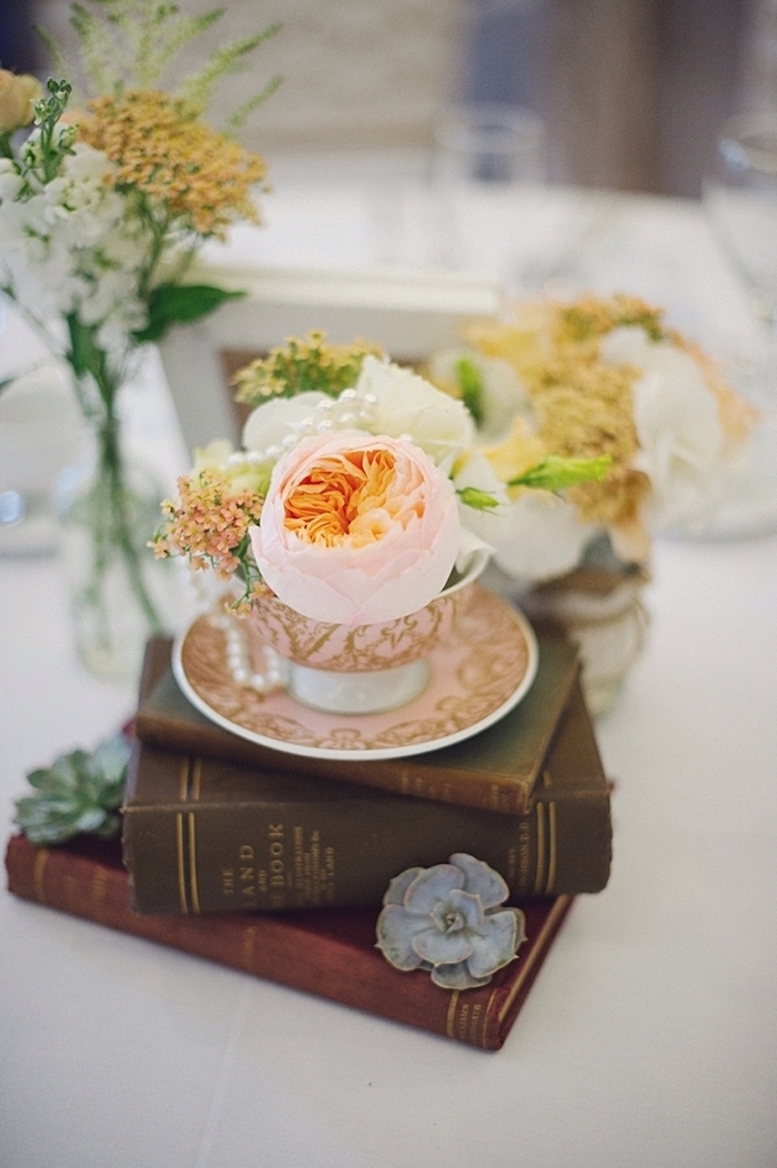 Prachtvolle Tischdekoration für Hochzeit, Blumen in Porzellantassen auf antiken Büchern