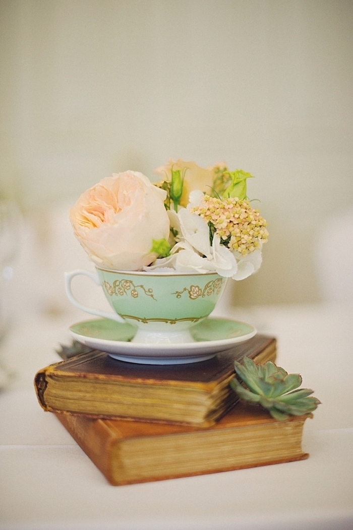 Blüten in Porzellantasse auf antiken Büchern, kreative und romantische Idee für Hochzeitsdeko