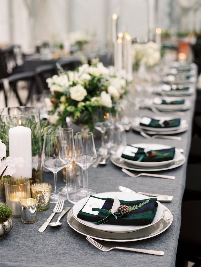 Wunderschöne Tischdekoration für winterliche Hochzeit, weiße Rosen und Kerzen, dunkelgrüne Servietten