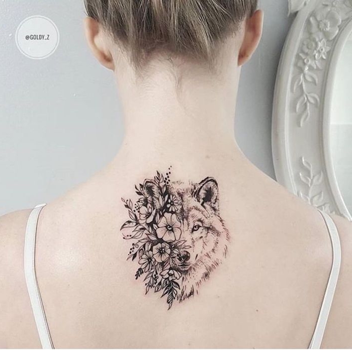 wolf tattoo für frauen, eine junge frau mit einem rücken tattoo mit einem weißen wolf und einem schwarzen wolf und vielen weißen und schwarzen blumen