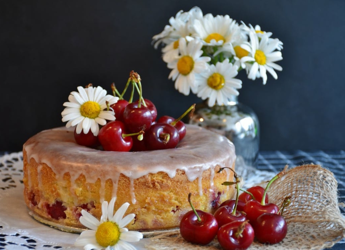Kirschen, Gänseblumen und ein süßer Kuchen mit lila Creme, einfache Tortenrezepte