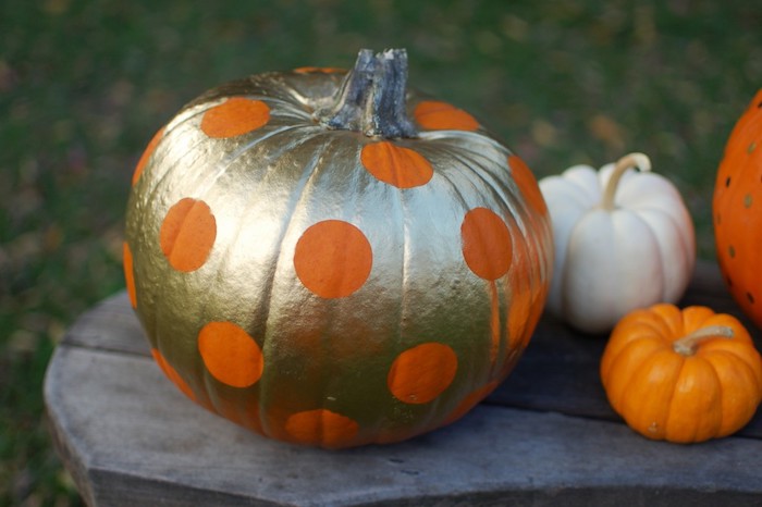 ein goldener halloween kürbis mit großen orangen punkten, kleine orange und weiße kürbisse und ein tisch aus holz, halloween deko selber basteln