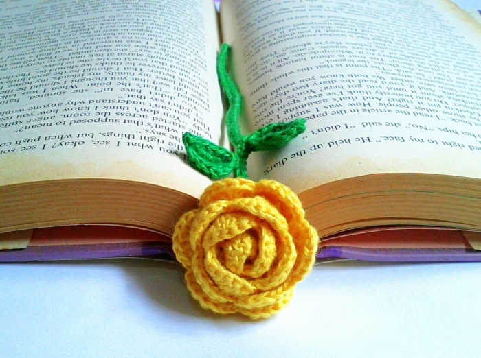 Lesezeichen häkeln, gelbe Rose mit grünen Stängel in einem Buch mit lila Umschlag