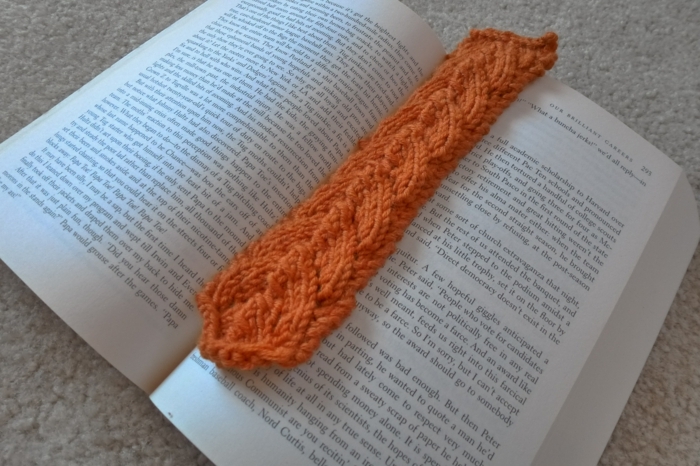 Lesezeichen häkeln, ein oranges Lesezeichen zwischen Blättern des Buches