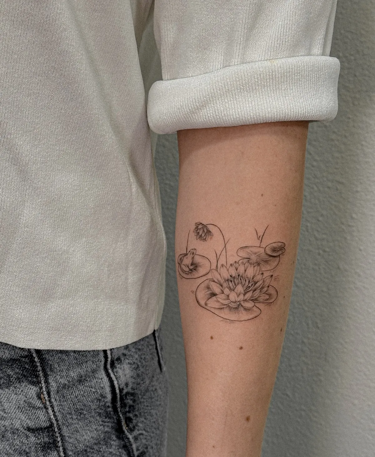 lotus tattoo am unterarm kleiner frosch