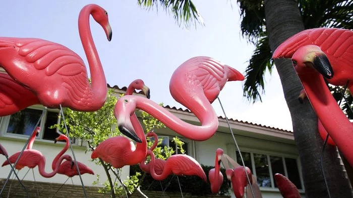 ein weißes haus mit einem garten mit grünen pflanzen und mit vielen pinken dekorativen flamingo, gartendeko ideen, flamingo deko