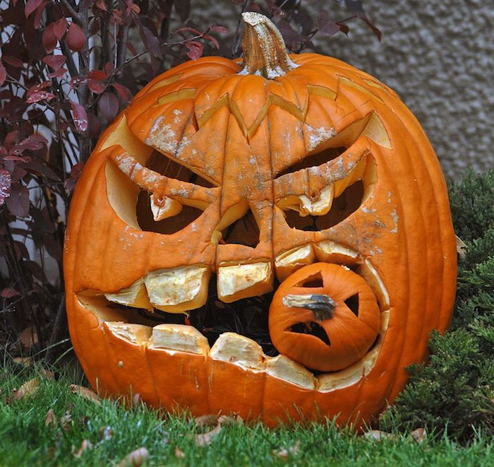 ein großer oranger halloween kürbis mit einem gruseligen hürbisgesicht mit gelben zähnen und großen augen, gruselige kürbisgesichter vorlagen 
