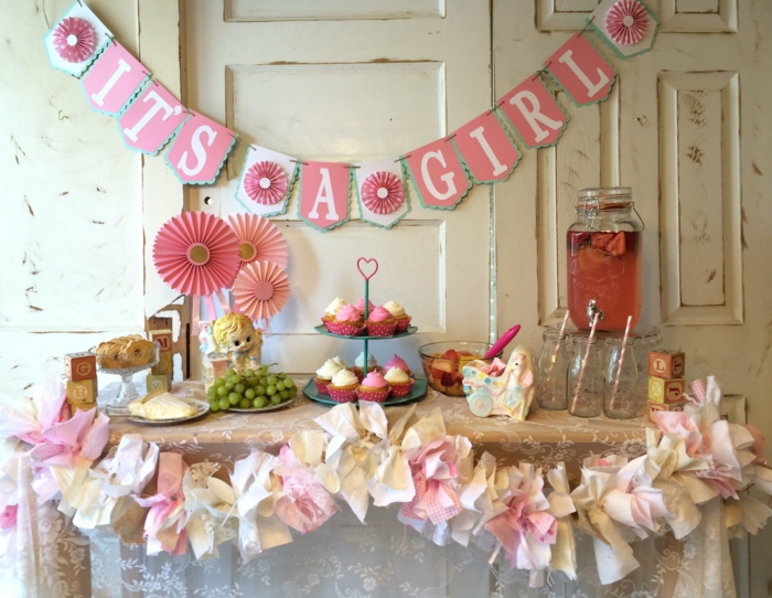 eine Girlande mit Buchstaben, rosa Cupcakes und Papierblumen, Deko für Babyparty