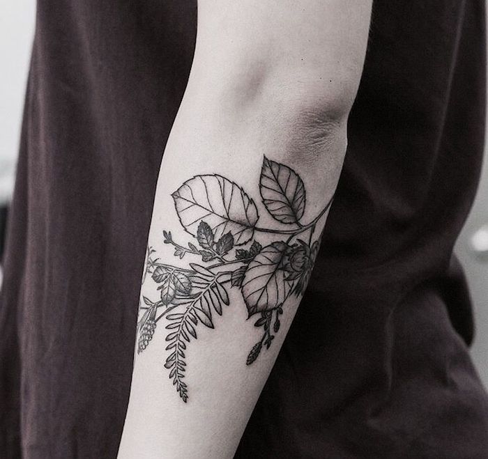 eine junge frau mit einer hand mit einem schwarzen tattoo mit vielen schwarzen und weißen blumen und blättern, frau tattoos ideen