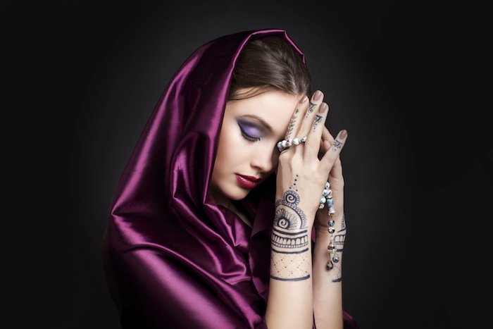 eine schwarze wand und eine junge frau mit einem tattoo mit henna moitiveb, tattoo am handgelenk, frauen tattoo ideen 