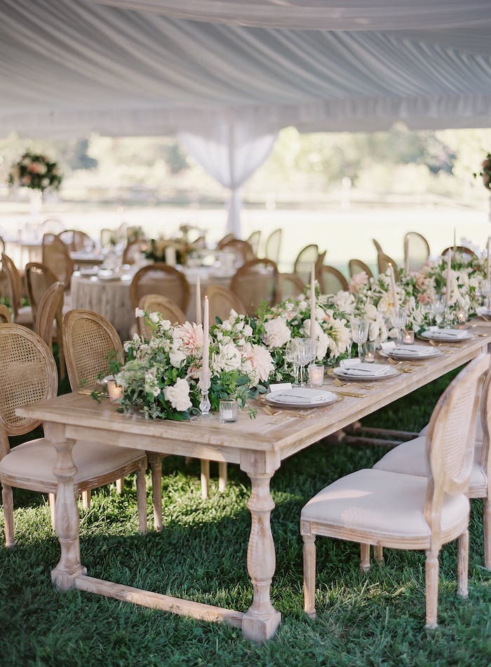 Hochzeitsdeko in Landhausstil, Holztisch und Stühle mit Altersspuren, weiße Blumen und Kerzen