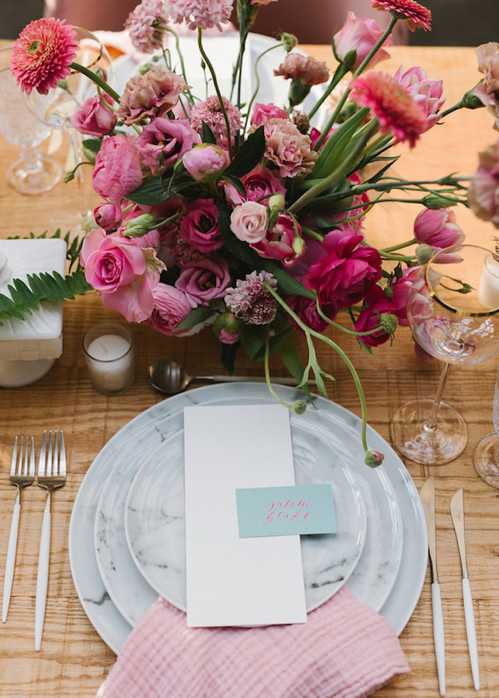 Wunderschöne Tischdeko mit vielen Blumen, Rosen Nelken und Pfingstrosen, rosafarbene Servietten und hellblaue Zettel mit den Namen der Gäste