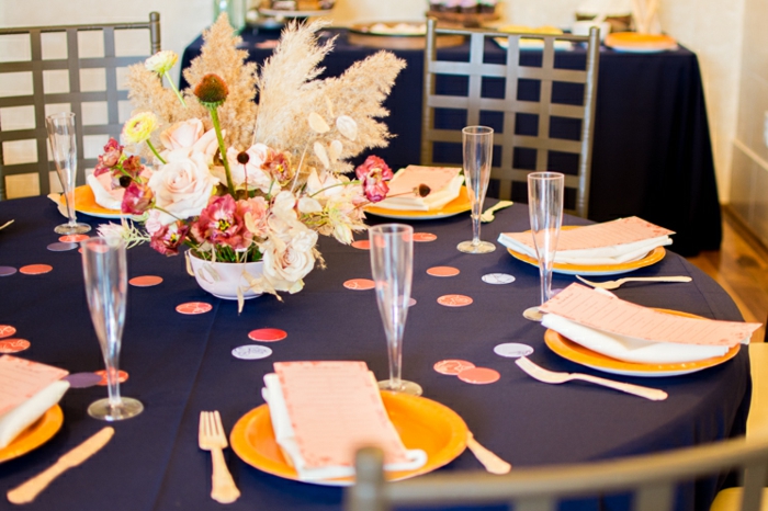 eine Tischdecke in dunkelblauer Farbe, gelbe Teller, hohe Gläser, Vase mit vielen Blumen
