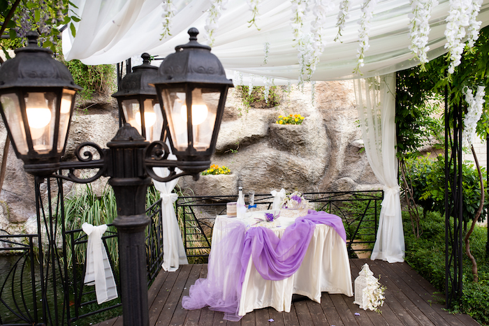 Hochzeitsfeier im Garten, prachtvolle Dekoration, weiße Decke und lila Tüll