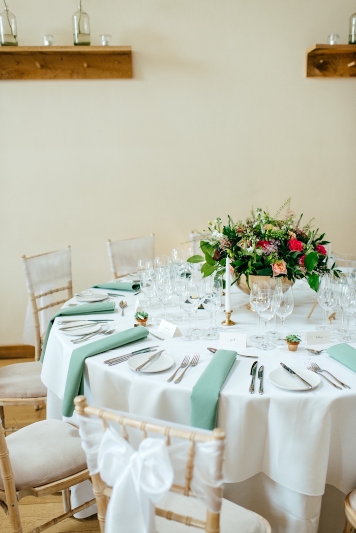 Stilvolle Tischdekoration für Hochzeit, weiße Tischdecke und grüne Servietten, viele Blumen