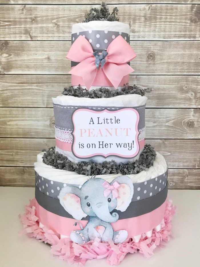 rosa und graue Torte, eine Aufschrift für das Baby, ein kleines Elefantchen, eine Schleife