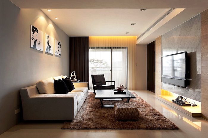 wohnzimmer deko ideen, gelbes led licht, brauner flauschiger teppich, drei bilder in schwarz und weiß