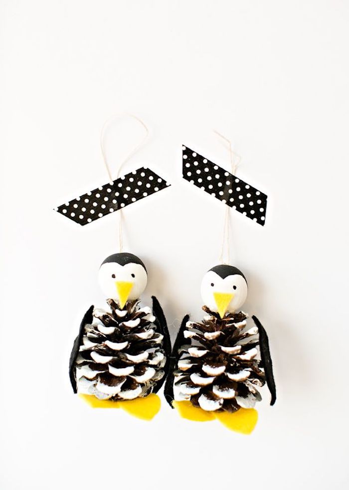 deko mit tannenzapfen basteln, zwei kleine schwarze pinguinen mit schwarzen augen und gelben beinen, pinguine aus tannenzapfen basteln