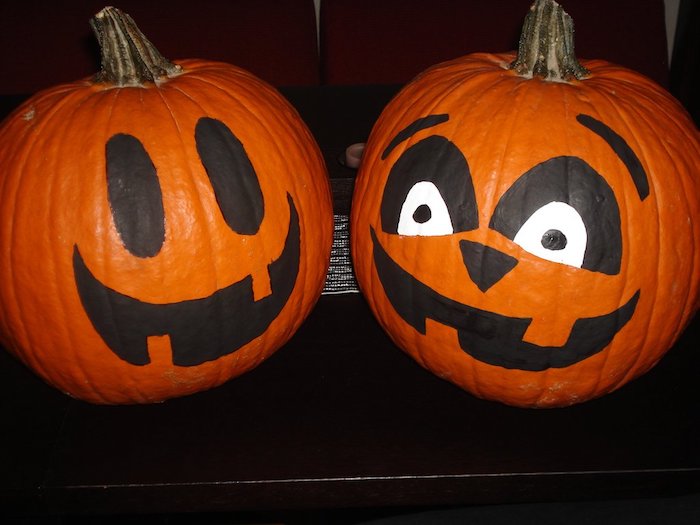 zwei orange kleine halloween kürbisse mit schwarzen großen augen und mit orangen zähnen, ein lustiges kürbis gesicht malen 