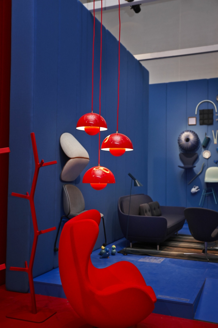 roter Sessel, hängende rote Lampen, Sofa in grauer Farbe, blaue Wände, welche Farbe passt zu Rot