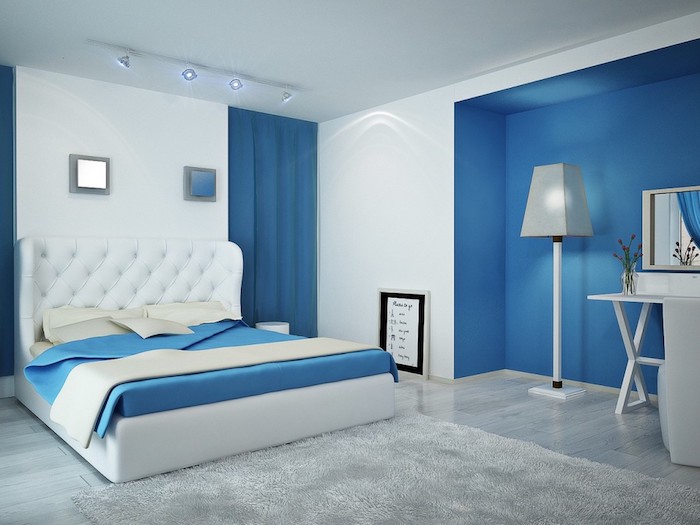 schlafzimmer einrichten ideen, ein bett mit weißen kissen und einer blauen decke, eine weiße lampe und ein grauer teppich, wandfarbe schlafzimmer blau