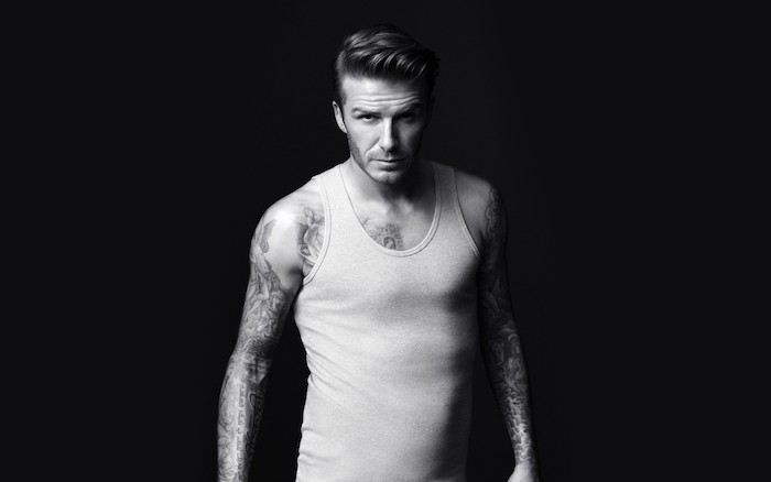 ein bild mit david beckam mit vielen schwarzen arm tattoos und mit einem weißen unterhemd, ein symbol für stärke mut und kraft tattoo ideen