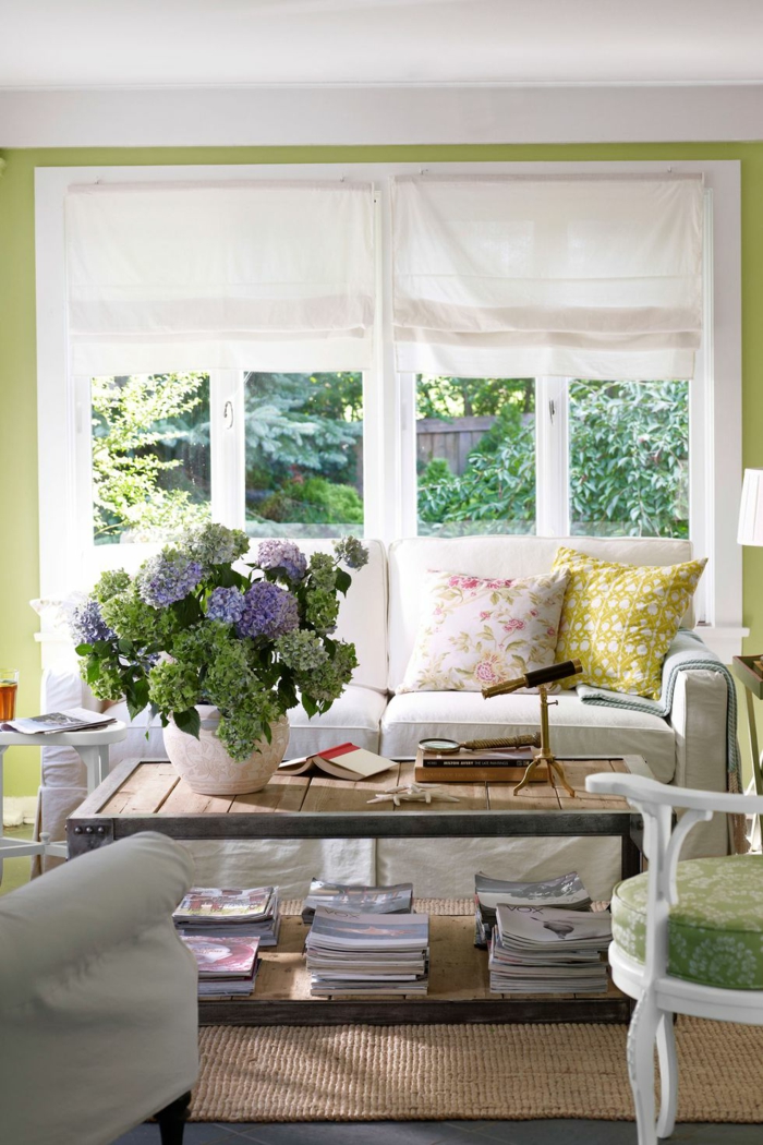 bunte wohnzimmer deko im raum, frische blumen, blau und lila, grün, gelb alle farben im raum, fenster, sofa, tisch