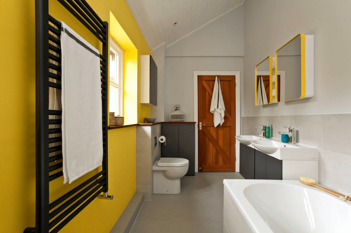 badezimmer sterichen ideen, eine weiße badewanne in einem badezimmer mit gelben und weißen wänden und mit weißen badmöbeln und einer tür aus holz