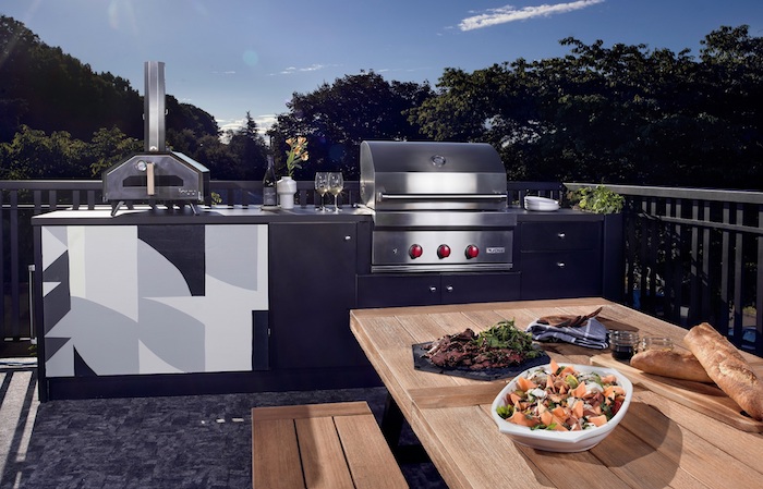 blauer himmel und eine schwarze außenküche mit einem ofen und einem elektroherd und bbq, ein brauner tisch aus holz