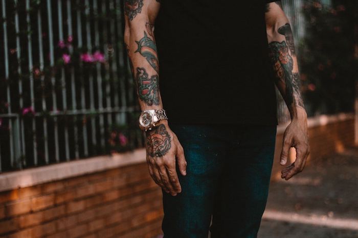 violette blumen und ein mann mit einer hand mit einer wei0en armbanduhr, hände mit vielen farbigen aquarell tattoos für männer