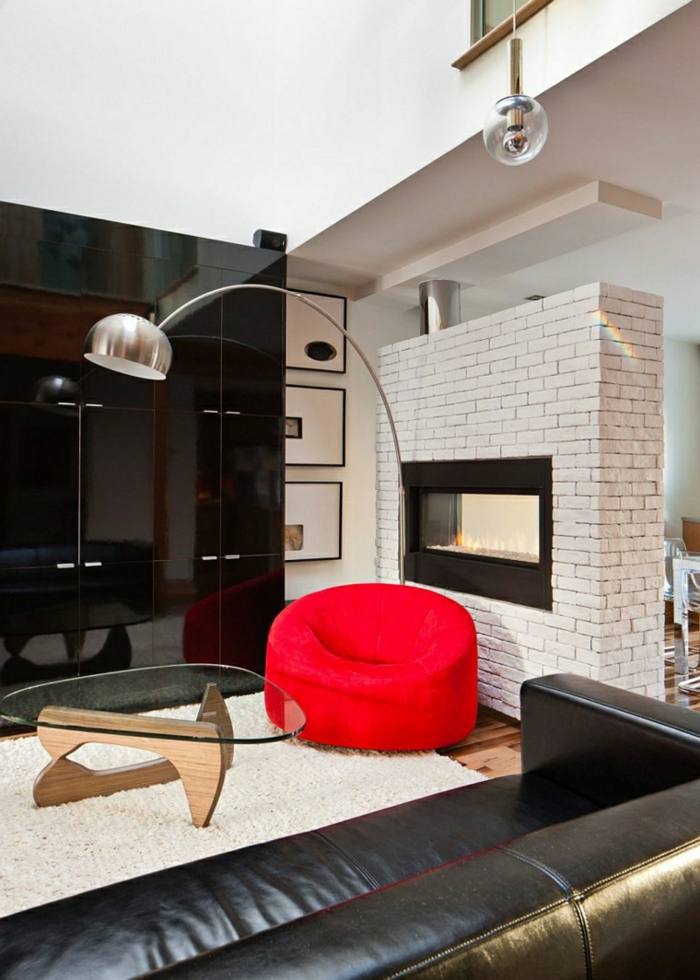 ein Kamin, ein roter Sessel, weißer Teppich, schwarze Wand, gläserner Tisch, schöne Farbkombination