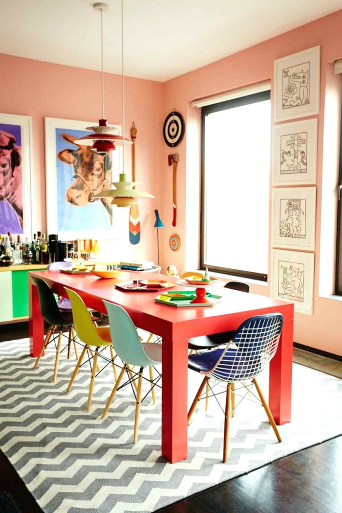roter Tisch, rosa Wandfarbe Küche, bunte Stühle, jeder in verschiedener Farbe
