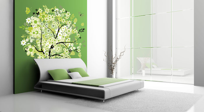 ein schlafzimmer mit einer grünen wand mit einem schwarzen baum mit weißen und grünen blumen, wandfarbe grün schlafzimmer, wand streichen ideen, bett mit grünen kissen
