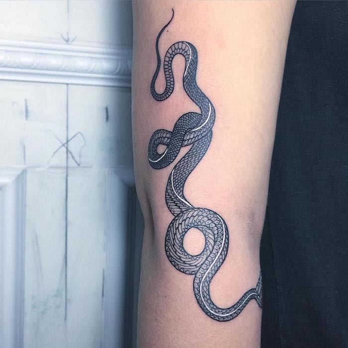 eine hand mit einer langen schwarzen schlange, ein schwarzer schlange tattoo arm, ein symbol für kraft und stärke