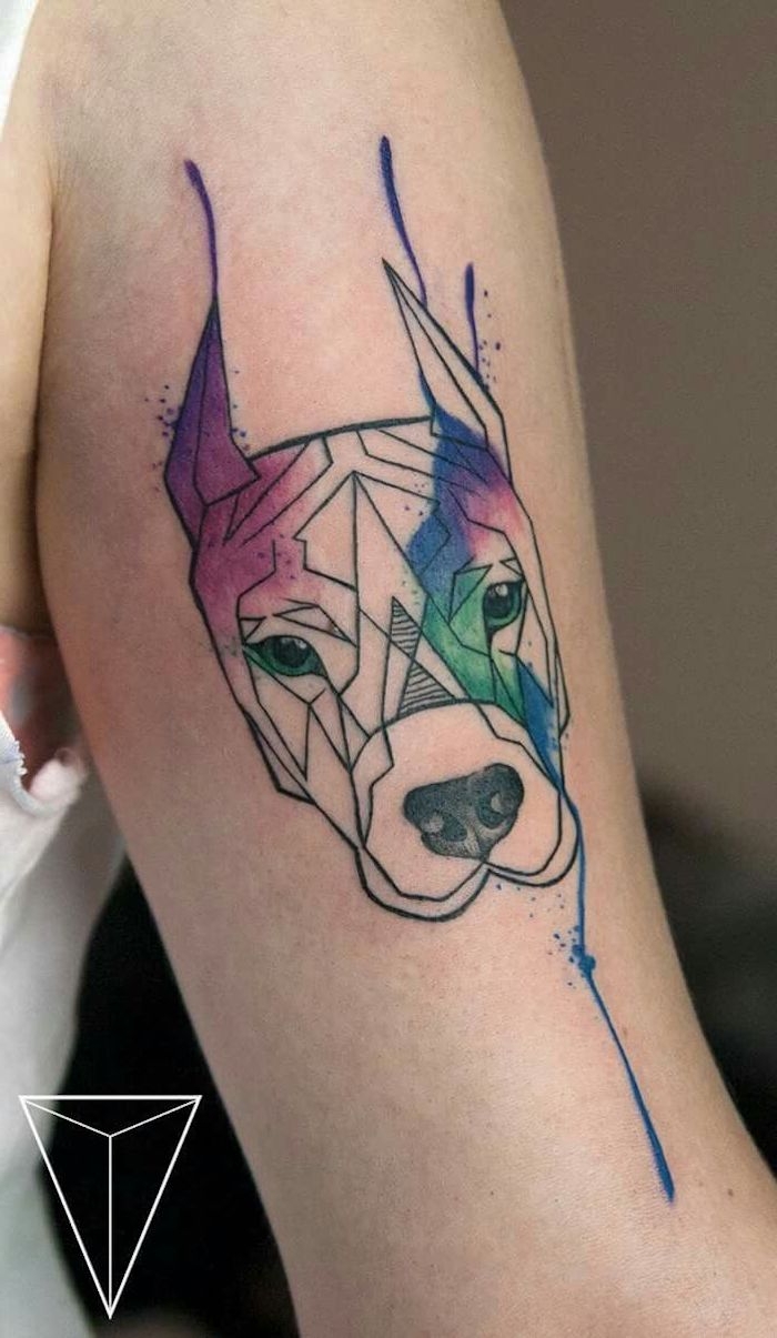 eine hand mit einem großen bunten tattoo aquarell mit einem hund mit einer schwarzen nase und mit grünen augen, hund tattoo arm