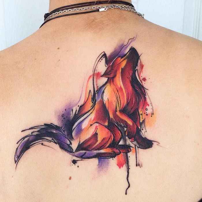 eine junge frau mit schwarzen ketten und mit einem rücken aquarell tattoo mit einem roten heulenden wolf, wolf tattoo rücken