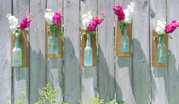 gartendeko ideen, vasen aus alten glasflaschen, weiße und rosa frühlingsblumen, diy anelitung