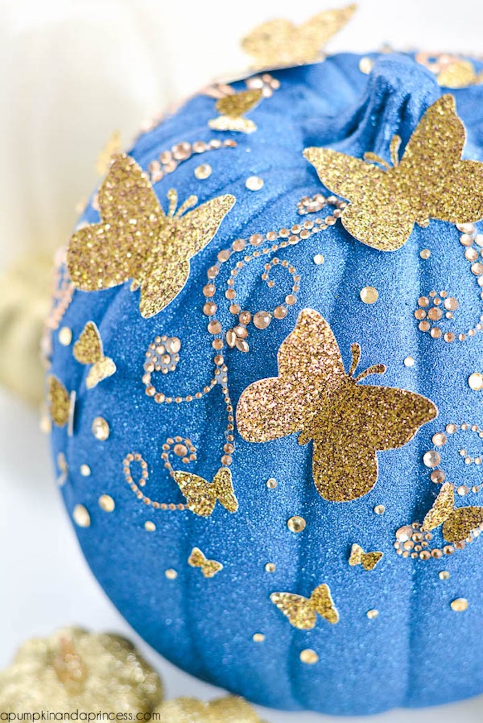 DIY Idee für Halloween Deko, Kürbis mit blauem Spray besprühen und mit kleinen goldenen Schmetterlingen verzieren