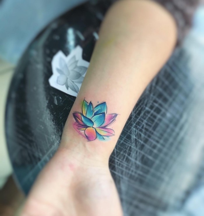 hand mit einem kleinen bunten watercolor tattoo am handgelenk und mit einer kleinen bunten blume, frauen tattoo motive