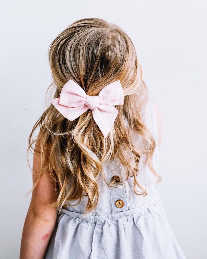 Wellige dunkelblonde Haare, rosafarbene Schleife, weißes Kleid mit Knöpfen, Frisuren für Mädchen