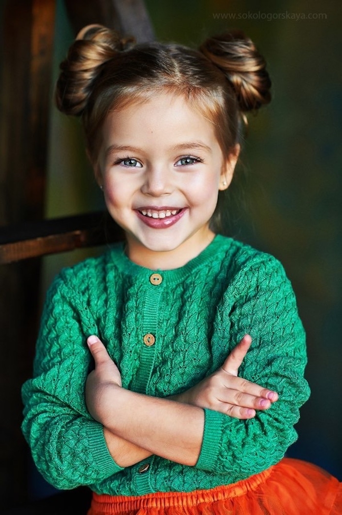 Double Bun, grüne Strickjacke und roter Tüllrock, süßes Mädchen mit blauen Augen und dunkelblonden Haaren