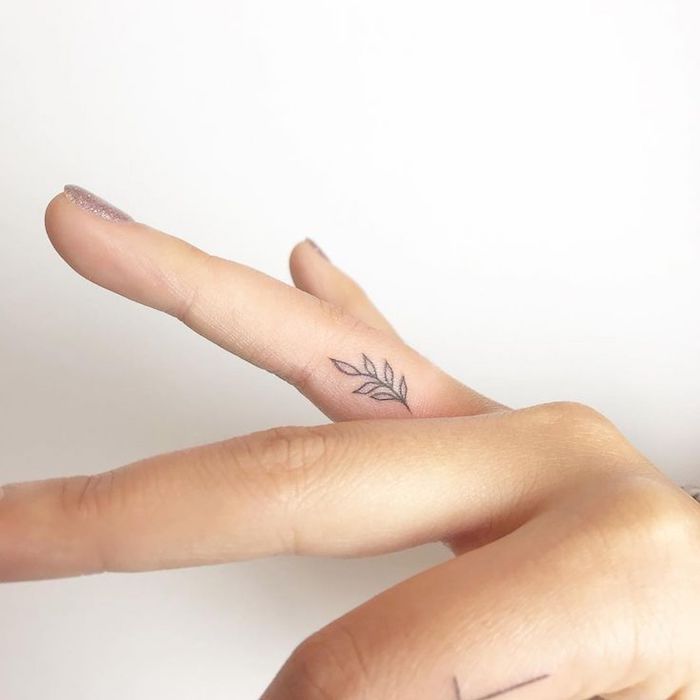 Kleines schwarzes Tattoo am Ringfinger, Glitter Nagellack, Tattoo Motive für Frauen