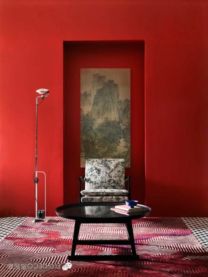rote Wände, graues Bild, ein schwarzer Tisch, gestreifter Teppich, schöne Farbkombinationen