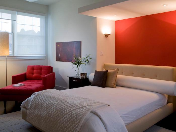 eine rote wand in einem schlafzimmer mit einemn bett mit kleinen violetten und beigen kissen und mit einem roten sofa und einer gelben lampe, schlafzimmer streichen ideen