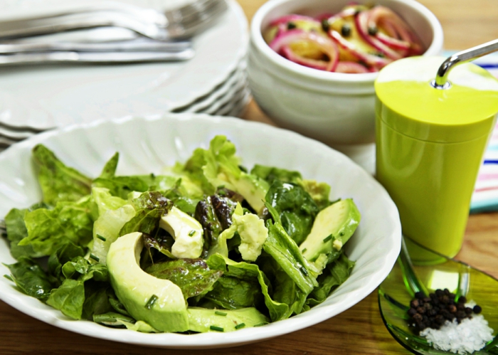 Avocado, grüne Salatblätter, mit Pfeffer und Salz gewürzt, roter Zwiebel als Dressing