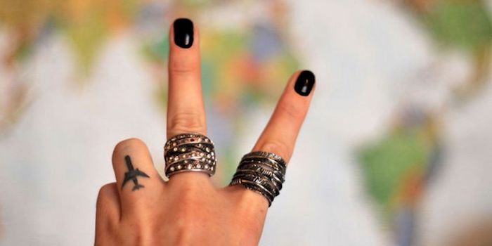 Kleines Flugzeug Tattoo am Ringfinger, massive Ringe, schwarzer Nagellack