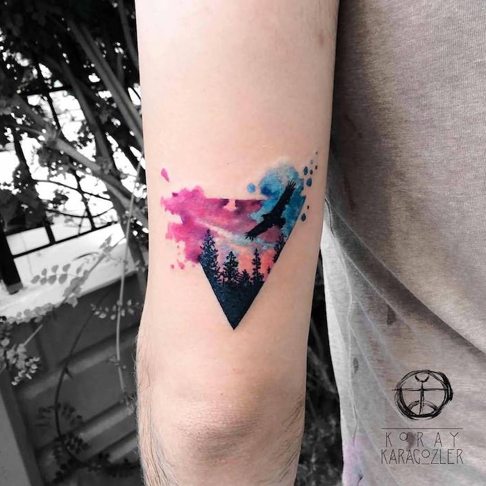 hand mit einem kleinen dreieck tattoo watercolor mit einem schwarzen fliegenden adler und einem wald mit schwarzen bäumen, vogel tattoo ideen